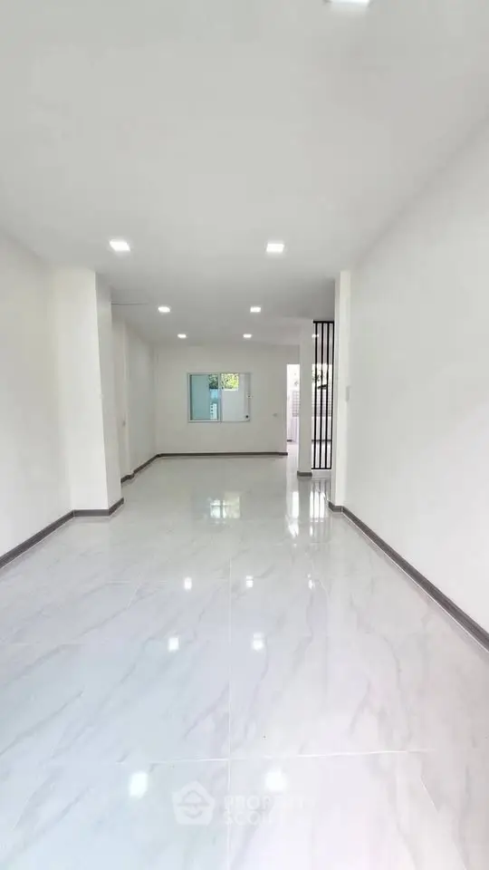 Spacious modern living room with sleek marble flooring and bright lighting.