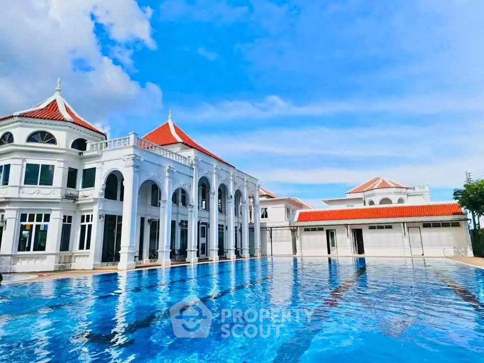 Luxurious mansion with a stunning pool and elegant architecture under a clear blue sky.