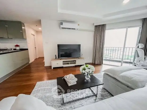 Spacious modern living room with balcony and sleek kitchen in open layout apartment.