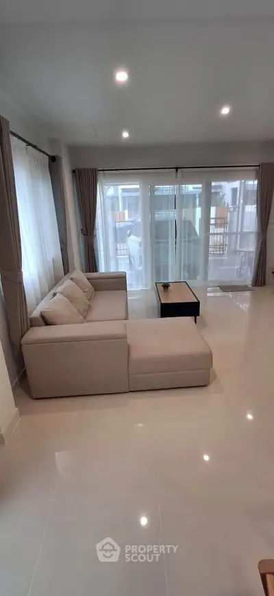 Spacious living room with modern sofa and large windows offering natural light.