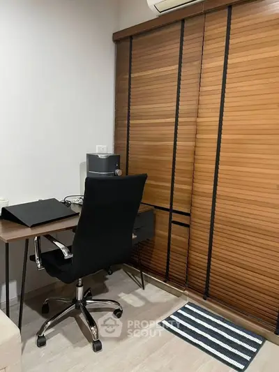 Modern study room with sleek desk, ergonomic chair, and wooden blinds for a cozy work environment.