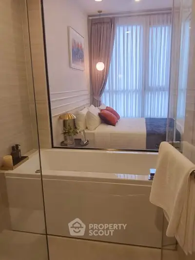 Modern bathroom with glass partition and view into stylish bedroom