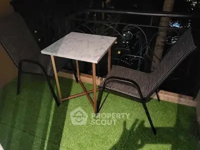 Charming balcony with cozy seating and lush artificial grass, perfect for relaxation.