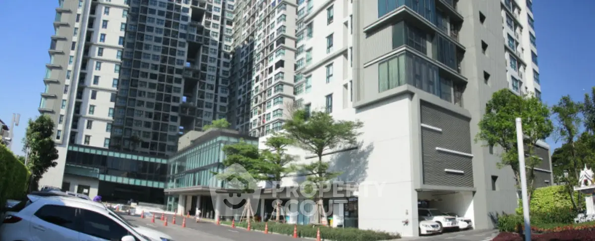 Modern high-rise residential building with sleek architecture and spacious parking area.