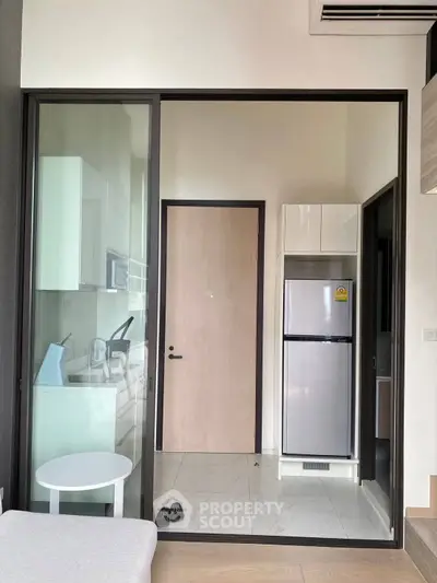 Modern kitchen with sleek appliances and glass sliding door in a stylish apartment.