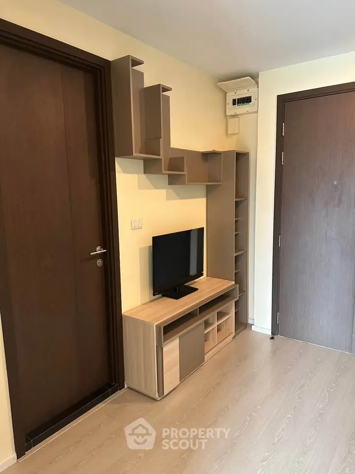 Modern apartment entrance with stylish wooden storage and TV unit