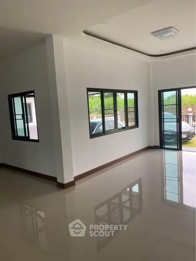 Spacious modern living room with large windows and glossy tiled floors