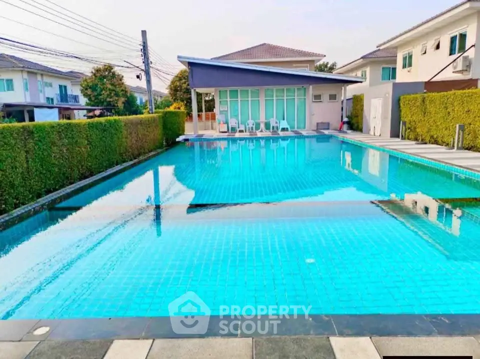 Luxurious residential swimming pool with modern clubhouse and lush greenery