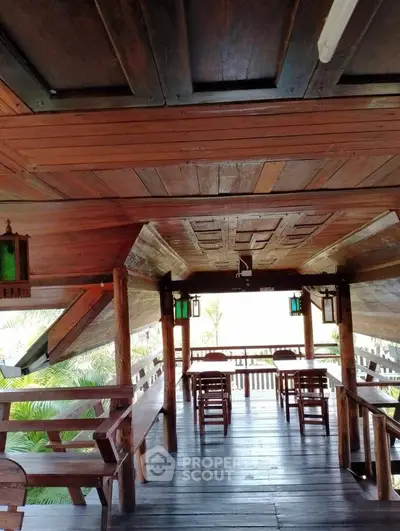 Charming wooden balcony with rustic seating and lush greenery view.
