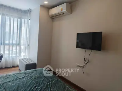Modern bedroom with air conditioning and wall-mounted TV, featuring large windows for natural light.