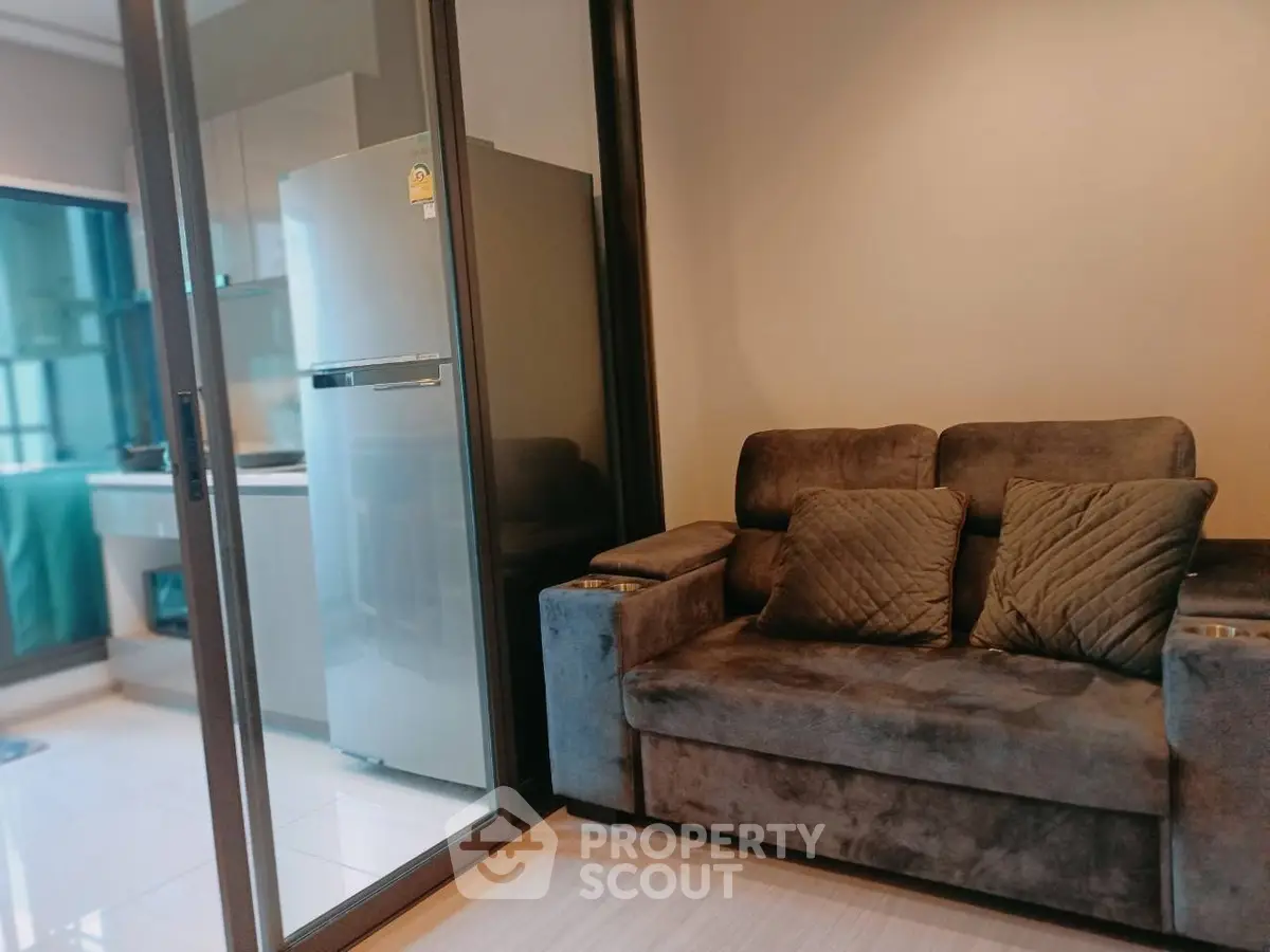 Modern living room with plush sofa and sleek kitchen area in open layout apartment.