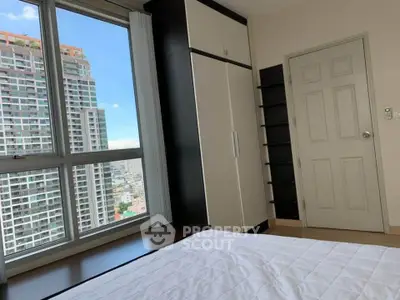 Modern bedroom with large window offering stunning city view in high-rise apartment.