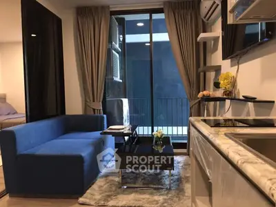 Modern living room with blue sofa, glass coffee table, and balcony view in stylish apartment.