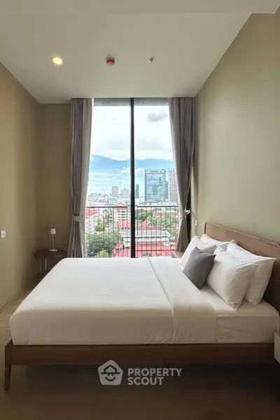 Modern bedroom with large window offering stunning city view, featuring a cozy bed and minimalist decor.