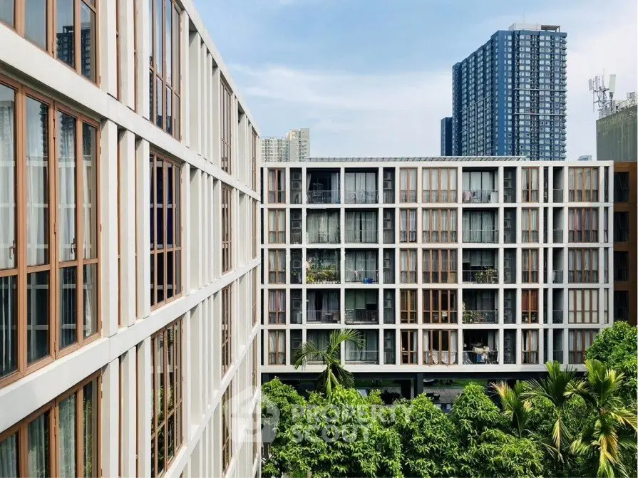 Modern apartment complex with lush greenery and city skyline view.