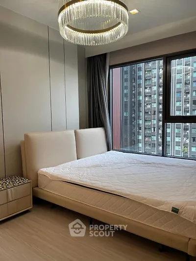 Modern bedroom with large window and elegant chandelier in urban apartment