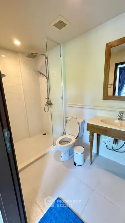 Modern bathroom with glass shower and wooden vanity in a bright, stylish home.