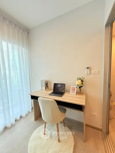 Cozy study nook with desk, chair, and laptop in bright room with sheer curtains.