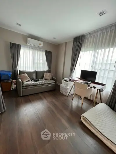 Modern living room with sleek furniture and natural light, featuring a cozy workspace and elegant decor.