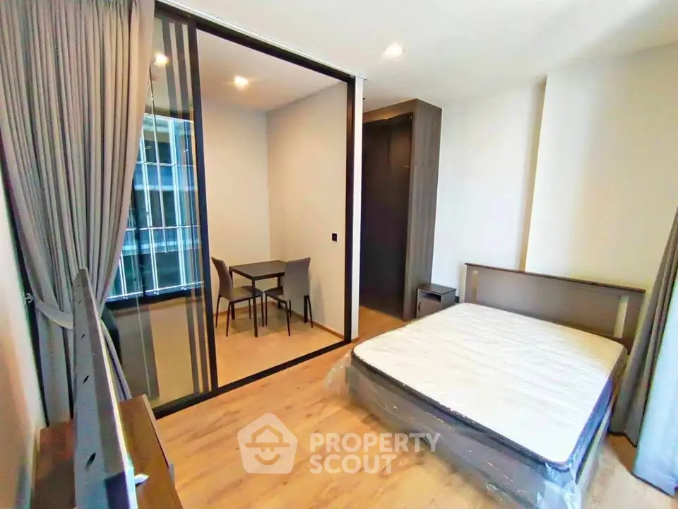 Modern bedroom with large window and adjacent study area in a stylish apartment.