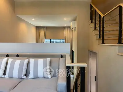 Modern loft-style living room with elegant staircase and cozy seating area.