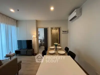 Modern open-plan living room with dining area and bedroom view in a stylish apartment.