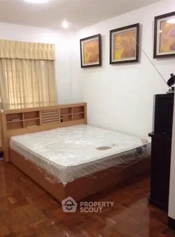 Cozy bedroom with wooden flooring and stylish artwork, perfect for relaxation.