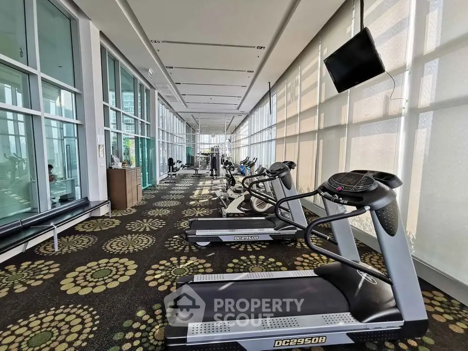 Spacious modern gym with state-of-the-art equipment and floor-to-ceiling windows.