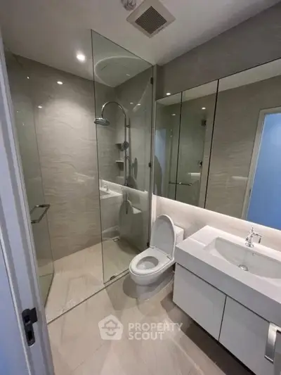 Modern bathroom with glass shower and sleek fixtures in contemporary apartment.
