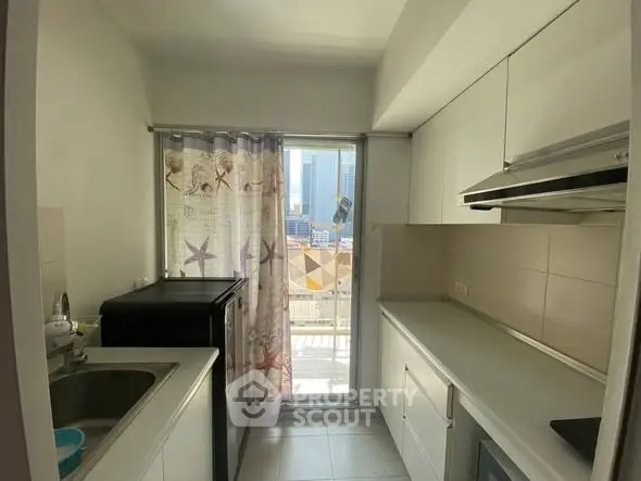 Modern kitchen with sleek cabinetry and natural light, featuring a balcony view.