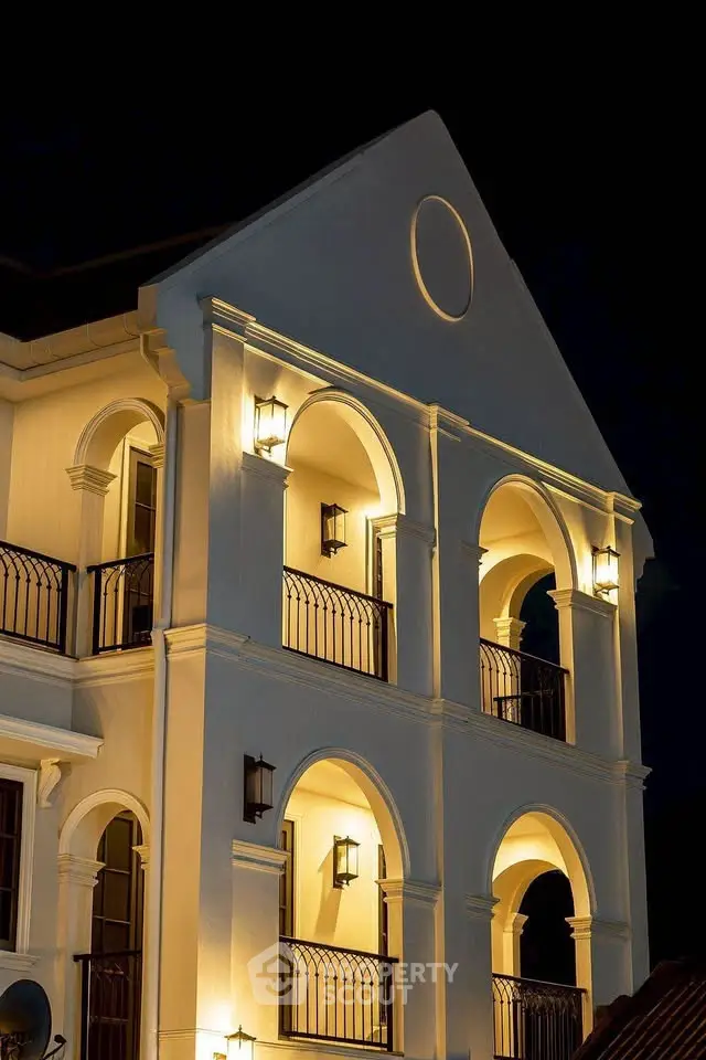 Elegant architectural facade with arched balconies and ambient lighting at night.