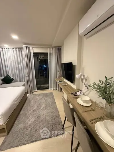 Modern studio apartment with cozy decor and balcony access, featuring a sleek workspace and comfortable living area.