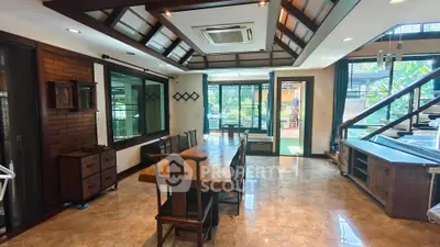 Spacious living room with wooden furniture and large windows offering garden view