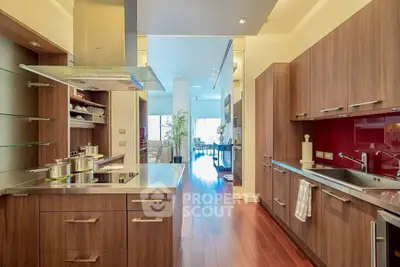 Modern kitchen with sleek wooden cabinets and stainless steel appliances in a luxurious apartment.