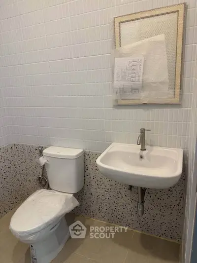 Modern bathroom with sleek fixtures and tiled walls, featuring a compact design.