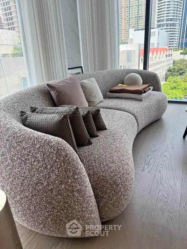 Stylish modern living room with curved sofa and city view, perfect for urban living.
