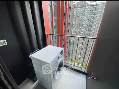Compact balcony with washing machine and city view in modern high-rise apartment.