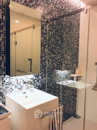 Modern bathroom with stylish mosaic tiles and sleek glass shower enclosure.