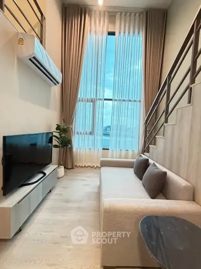 Modern living room with high ceilings and large windows, featuring a stylish sofa and flat-screen TV.
