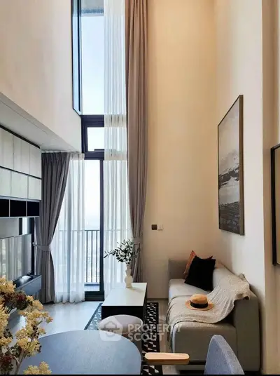 Modern living room with high ceilings and large windows offering stunning views.