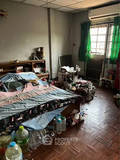 Cozy bedroom with parquet flooring and air conditioning, featuring a large bed and ample natural light.