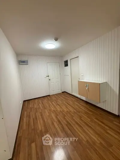 Spacious empty room with wooden flooring and modern wall cabinet