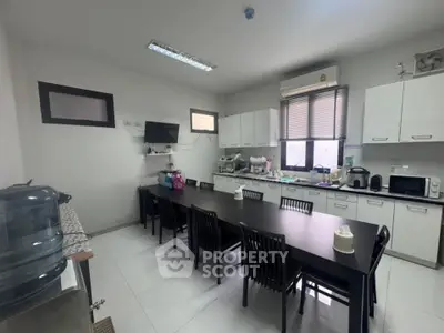 Spacious kitchen with modern appliances and large dining table, perfect for gatherings.