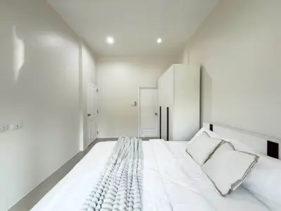 Modern minimalist bedroom with white walls and cozy bedding