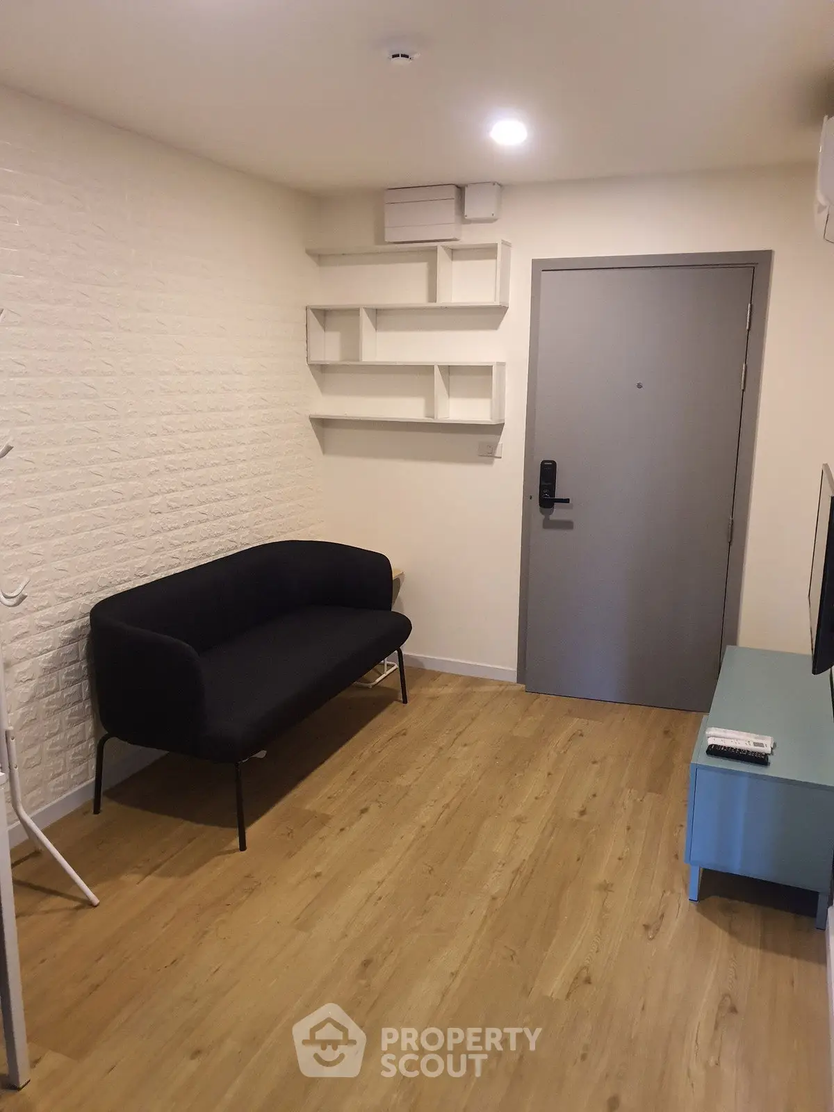 Modern apartment entrance with stylish black sofa and wall-mounted shelves