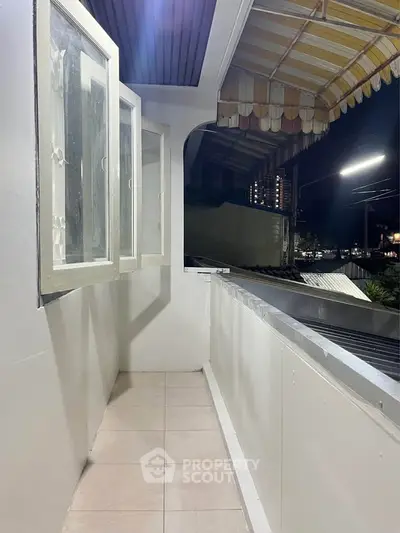 Charming balcony with night view, featuring open windows and tiled flooring, perfect for relaxation.