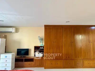 Spacious bedroom with wooden wardrobe and TV unit, ideal for comfortable living.