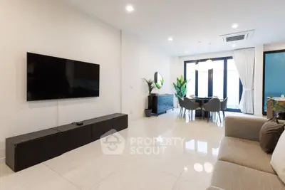 Spacious modern living room with sleek furniture and large TV, perfect for relaxation and entertainment.