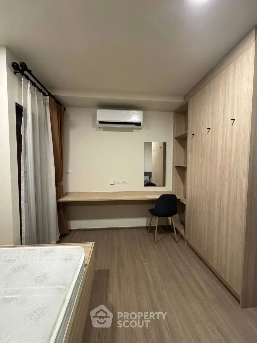 Modern bedroom with built-in wardrobe and air conditioning, featuring a minimalist design and wooden flooring.