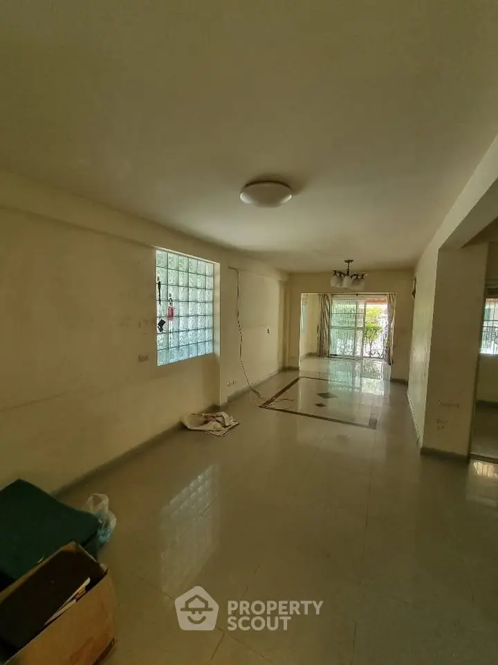 Spacious living room with large windows and tiled flooring in a modern apartment.